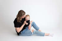 Edmonton studio photo of mom and baby boy sitting on white savage seamless paper