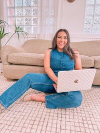 Natalie in a Denim Romper Sitting on the floor with a computer