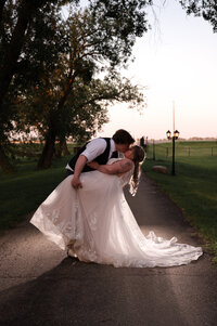 Groom dips his bride and kisses her during wedding reception at Falkenberg Stables 