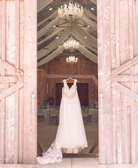 White wedding dress hanging in barn doorway