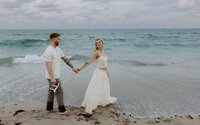 couple holds hands on beach in south florida