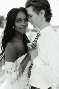 Interracial couple dances together as bride looks on toward the camera.