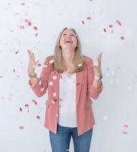 Maureen throwing pink confetti and looking up smiling