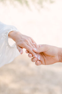 couple holding hands on the beach during an engagement session