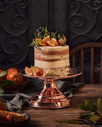 coppermill kitchen cakestand with large cake on top with oranges on decorated table