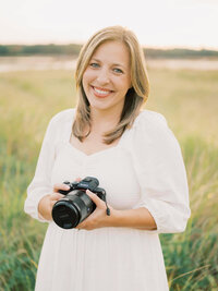 photographer posing in all white on the beach with sony camera by carrie pellerin