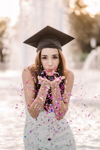 Graduate blowing confetti in the UCF reflection pond by Orlando Graduation photographer Haleigh Nicole