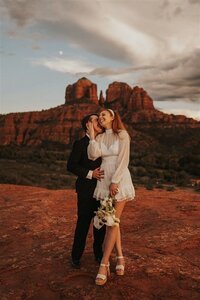 A couple leans in for a kiss as the sun starts to set in Sedona Arizona.