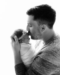 father kissing newborn baby girl for photoshoot