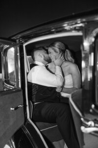 bride and groom sitting in the back seat of a car kissing