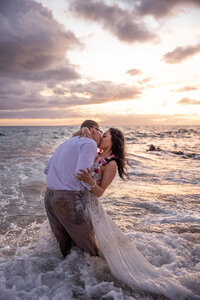 Maui Elopement Photographer captures couple kissing in water after intimate hawaii beach wedding