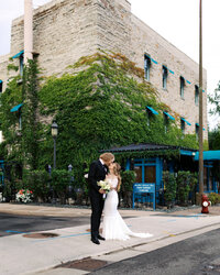 Newlyweds standing together at Nicollet Island Inn kissing in the romantic moment in downtown. Minneapolis.