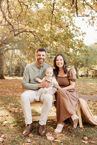 Chelsea  with her husband holding their baby posing for the camera during a family photoshoot