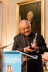 Man holds glass award while giving an acceptance speech at an award ceremony