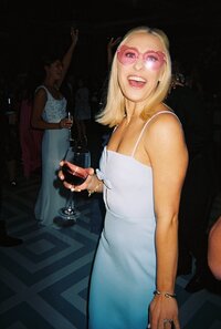 Flash photo of bridesmaid at reception wearing pink heart sunglasses and holding a wine glass
