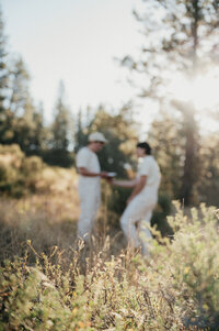 Two people out of focus wearing white clothing and standing in a sunlit field representing nature and adventure based counseling in boise idaho.