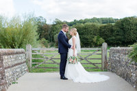 Beautiful natural light romantic landscape portrait of the bride and groom at Farbridge barn in West Dean on their wedding day
