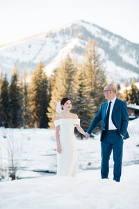 bride and groom holding hands in the snow