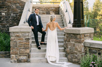 This gorgeous luxury photograph captures the bride and groom on the stone steps of the Banff Springs Hotel during an evening stroll around the property. The iconic hotel's elegance and the couple's sophisticated style create a timeless and high-end moment on their wedding day.