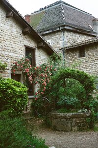 A lush green garden area against a stone cottage in france