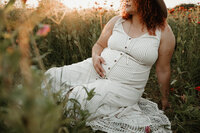 Maternity mom sitting among wildflowers during a serene outdoor session with Charlotte family photographer Tonya Cassibry.