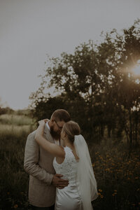 Bride and groom just taking a moment together on their wedding day while the sun shines through some trees beside them, surrounding them with the most magical glow.