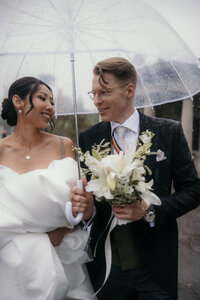 Happy wedding-couple under an umbrella looking at each other.