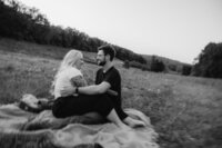 Couple sitting on a blanket in a field.