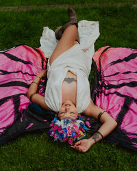 Flat-lay style image of artist lying on a pink picnic blanket in a whimsical floral crown – creative portrait by Mewphotovideo