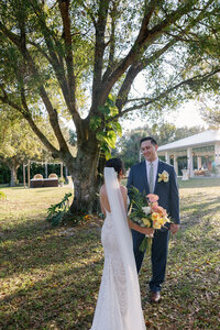 couple looking at each other while standing in front of an oak tree, the girl is in a wedding gown