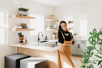 Woman leans against the counter in her styled kitchen