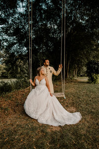 Bride and groom posing on an old swing in a big tree
