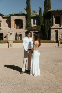 bride and groom standing in front of building