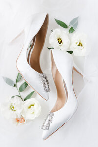 flat lay of white bridal shoes and white flowers