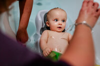 A baby taking his bath and playing with the water