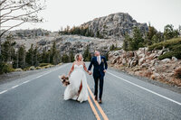 Black and white photo of a bride playfully kicking up her heels while stepping out of a vintage car, capturing a timeless and elegant elopement moment.