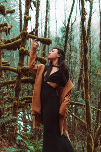 Creative professional dressed in earth tones surrounded by tall trees – adventurous branding session by Mewphotovideo