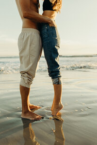 An image of two people pressed close together near the ocean in Southern California
