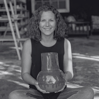 Jessica wearing a white blazer, smiling as she writes in her planner