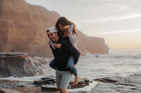 Couple laughing and surrounded by Sunset Cliffs and ocean in San Diego