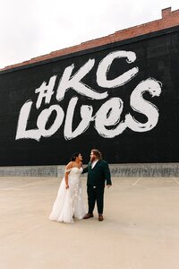 bride and groom in from of KC Loves sign in downtown Kansas City