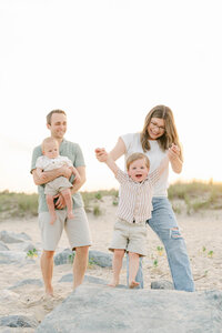 Mother with long brown hair and flowy dress walks the beach in Delaware with her daughter during a family photo session