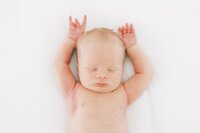 Newborn photos asleep on bed with arms up during photo session with Dallas Newborn Photographer Amanda Carter