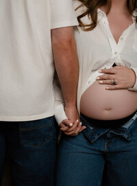pregnant woman with hand on belly and partner facing opposite way