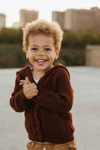 Little boy smiling at the camera while wearing a red sweater