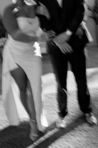 Motion blur photo of newlywed couple walking hand in hand, featuring a modern bridal gown with thigh slit, captured in Lakeland Florida.