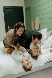 Chloé et son chéri faisant des chatouilles à leurs enfants sur un lit et capturés par Laura, photographe famille en Vendée.