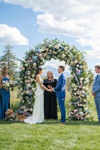Couple stands in front of flower arch
