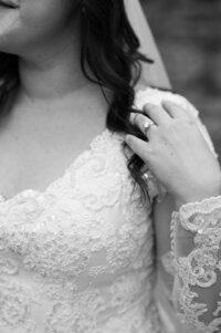 A close up of a person with their hand on their shoulder showing off a wedding ring
