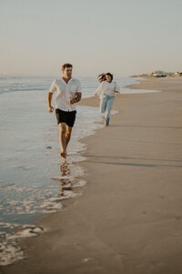 Couple playing tag along the California coast during their engagement session.